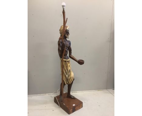 A carved wood lamp standard modelled as a beggar with a bowl and a staff, height 168cm