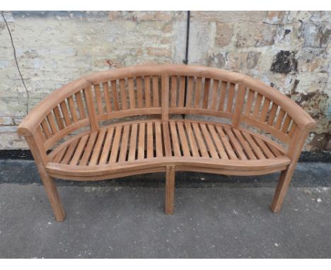 A teak banana-shaped garden bench