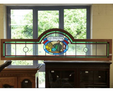 A Hudsons stained glass panel with central panel depicting a gentleman with monocle lifting a dome formed as the globe (width