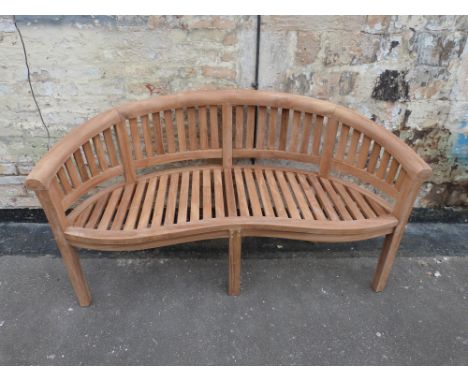 A teak banana-shaped garden bench