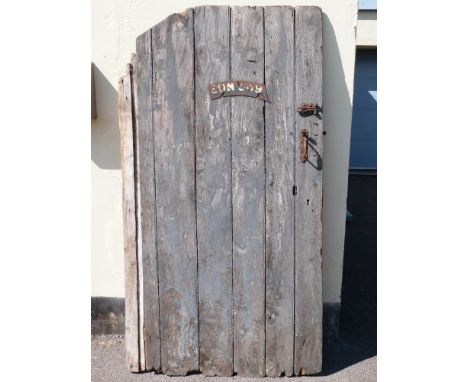 A vintage planked wooden door with fittings, mounted with vintage motorcycle number plate EOM 389