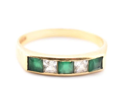 A hallmarked 18ct gold, emerald and white stone ring. The 18ct yellow gold ring having three channel set synthetic emeralds i