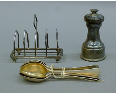 A silver toast rack, silver teaspoons and a silver pepper grinder. The latter 8.5 cm high. 169.2 grammes of weighable silver.