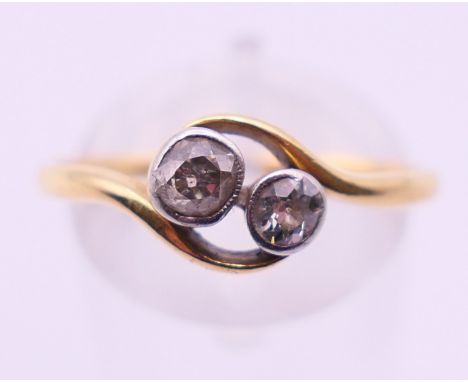A gold and diamond two-stone crossover ring. Ring size S.