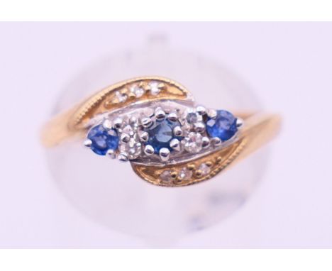 A 9 ct gold, diamond and sapphire crossover ring. Ring size O. 