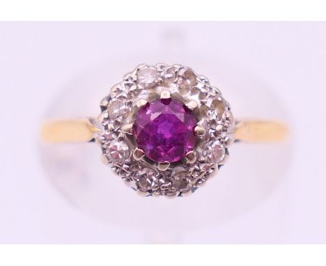 An 18 ct gold, ruby and diamond flower head ring. Ring size J. 