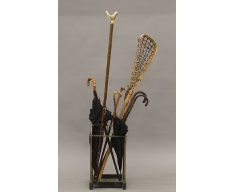 A Victorian brass and iron stick stand together with various walking sticks umbrellas etc. The stand 63 cm high.