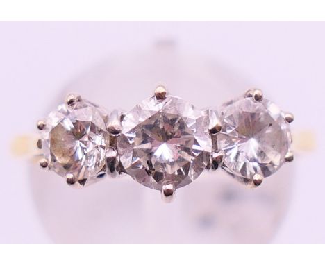 An 18 ct gold three stone diamond ring. Ring size P. 