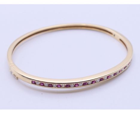 A 9 ct gold, diamond and ruby bangle form bracelet.  6.5 cm diameter, 4 mm high. 13.5 grammes total weight.