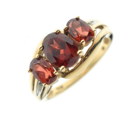 Three-stone garnet crossover ring, the yellow metal shank stamped '9K', size P½, 3.4g gross approx