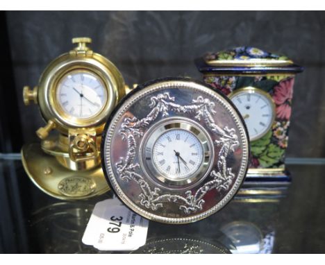 A silver circular shaped bedside clock, London 1994, together with a Masons porcelain miniature mantel style clock and a case