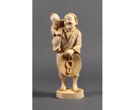 A Japanese carved ivory okimono, Meiji period (1868-1912), of a man holding a broad-brimmed hat at his waist with a child at 