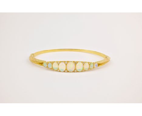An 18ct yellow gold, opal and diamond bangle, the front set with with a row of graduated cabochon opals with brilliant cut di