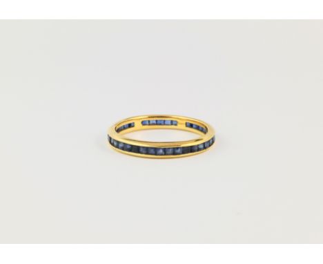 An 18ct gold and sapphire eternity ring, featuring a continuous row of channel set calibré cut sapphires, ring size R 