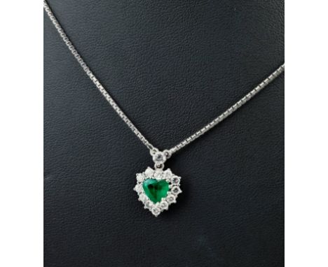 An 18ct white gold, emerald and diamond heart shaped pendant necklace, featuring a heart cut emerald measuring approximately 