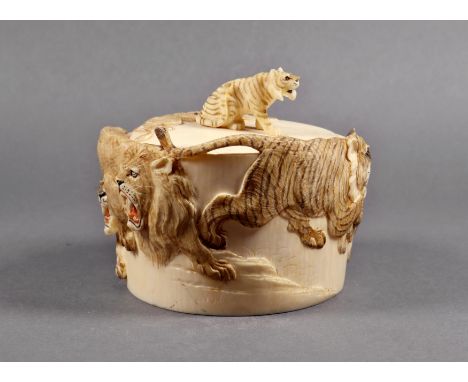 A Japanese carved and stained ivory lidded box, Meiji period (1868-1912), the sides carved in bas relief with lions and tiger