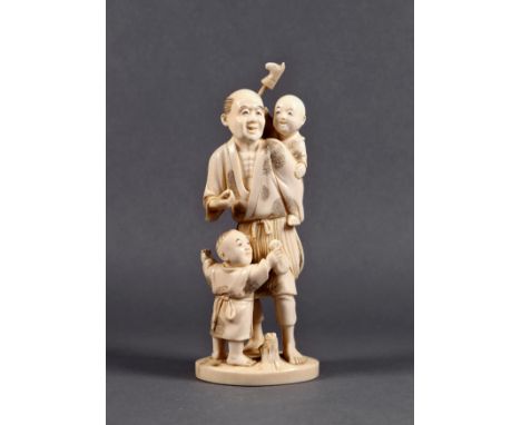 A Japanese carved ivory okimono of a father and children, Meiji period (1868-1912), the man standing with a child on one shou