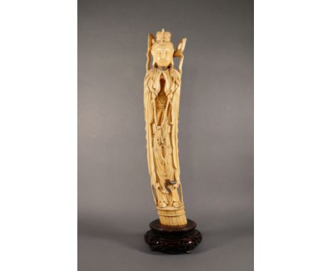 A Chinese carved one-piece ivory figure of Guanyin, Qing Dynasty, with fingers touching in prayer, a long string of prayer be