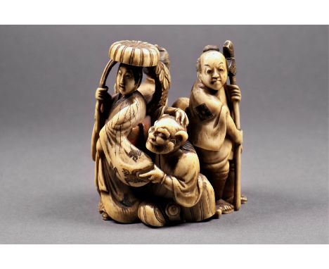 A Japanese carved ivory okimono, 18th / 19th century, depicting two ladies and a man with an axe standing beside a kneeling m