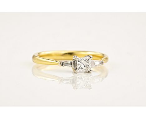 An 18ct yellow and white gold diamond trilogy ring, with a princess cut centre stone between two tapered baguette cut diamond