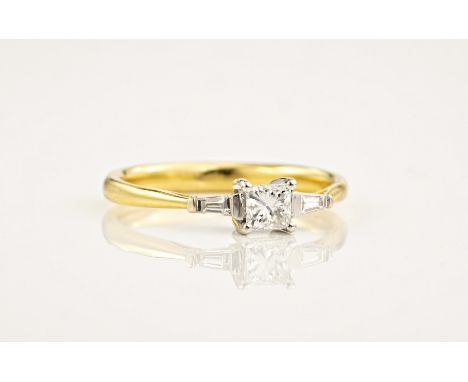 An 18ct yellow and white gold diamond trilogy ring, with a princess cut centre stone between two tapered baguette cut diamond