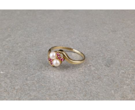 A 9ct gold, ruby and seed pearl twist ring, the to seed pearls flanked by trios of small round cut rubies, size O. 