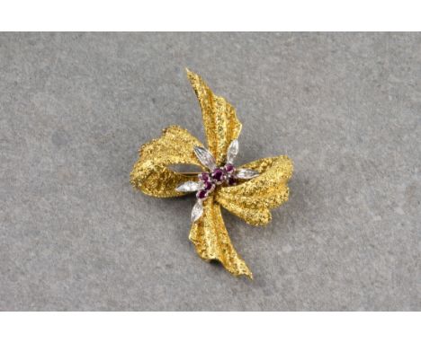 An 18ct gold, ruby and diamond floral bow brooch, formed of textured gold ribbon with floral ruby and diamond detailing to th