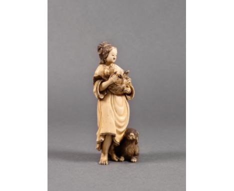 A Japanese carved ivory okimono, Meiji period (1868-1912), of a woman standing with a dog at her feet and holding a puppy in 