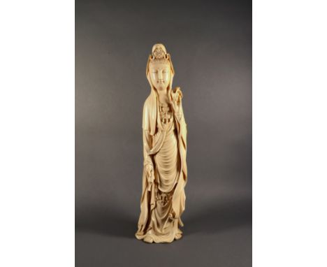 A Chinese carved ivory figure of Guanyin, Qing Dynasty, with a small seated Buddha in her headdress holding an inverted vase 