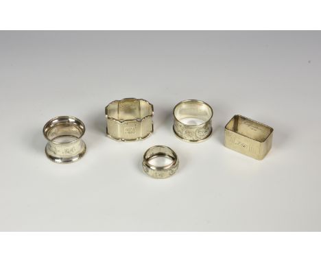 A collection of five silver napkin rings, varying forms, dates and makers to include a shaped oval, engine turned example by 