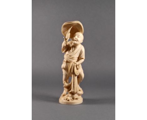 A Japanese carved ivory okimono of a fisherman, Meiji period (1868-1912), standing on rocks with waves breaking around, holdi