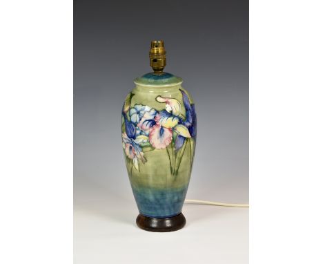 A Moorcroft Lily pattern table lamp, of baluster form, tube lined flowers in pinks, purples and blues on green ground, having