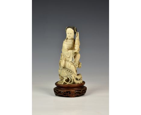 A Japanese carved ivory okimono, Meiji period (1868-1912), of an elegant lady seated upon rockwork, holding a musical instrum