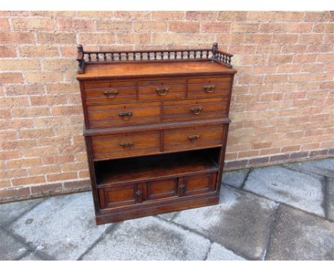 A WALNUT SIDE CABINET  with spindle gallery to top, above an arrangement of seven drawers, shelf and sliding doors, 90cm wide