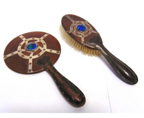 AN ARTS & CRAFTS COPPER HAND MIRROR AND HAIR BRUSH  both with studded white metal strap work decoration and an enamel boss to