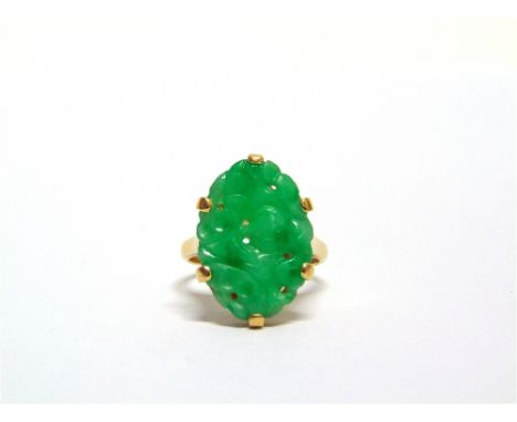 A JADE PANEL RING stamped '18K', the carved and pierced oval panel approximately 18mm by 13.2mm, finger size M, 4.7g gross