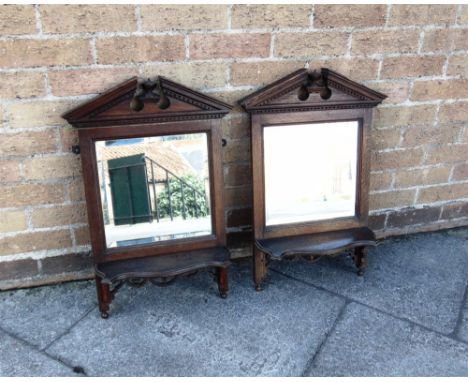 A PAIR OF OAK MIRRORED WALL SHELVES  with architectural broken pediment friezes above mirror and shaped shelf, open fret carv