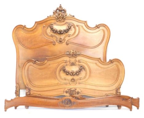 A heavily carved French walnut double bed frame, centred by a pierced scroll and floral arrangement, above a panel of floral 