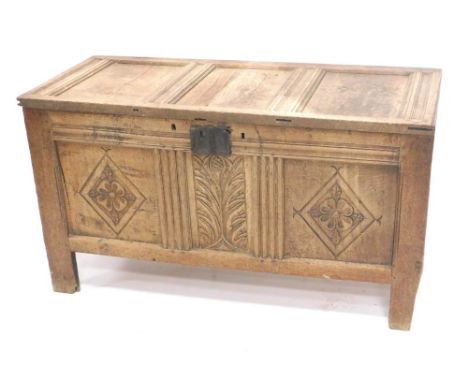 An 18thC oak three panel coffer, the rectangular lid raised above an iron lock with diamond and floral pattern carving on sti