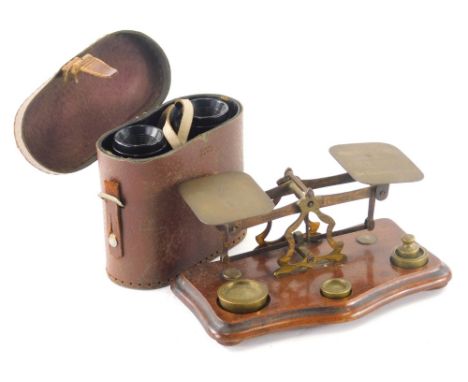 A 20thC brass and mahogany postal scale, on serpentine base with various weights, 20cm wide, and a pair of leather cased bino