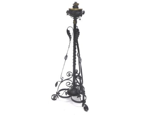 A late 19thC/early 20thC wrought iron floor lamp, with an oil lamp fitting and reservoir, the base decorated in Art Nouveau s