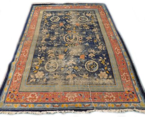 An early 20thC Chinese carpet, with a design of stylised bats, flowers, leaves, on a navy ground with multiple borders, (AF),