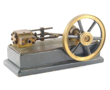 A 20thC metal stationary engine, with front cog and back piston on square wooden base, partially painted green, 18cm wide.