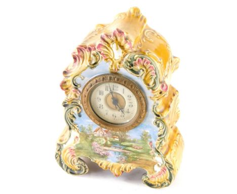 An Edwardian pottery mantel clock, with 9cm diameter Arabic dial elaborately decorated in a scroll case in yellow and green, 