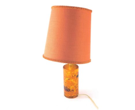 A 20thC retro table lamp, with orange shade, the cylindrical resin mock glass base in amber colours, unsigned, 53cm high.WARN