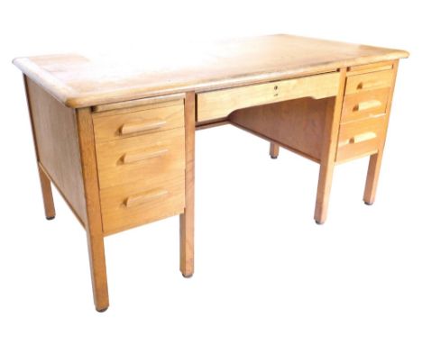 A mid 20thC light oak pedestal desk, by Abbess, numbered A301, with a cross banded top, on chamfered legs, 80cm high, 148cm w
