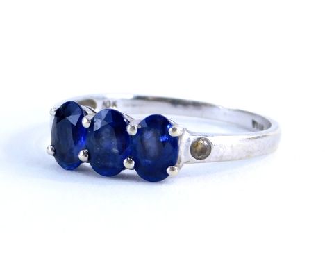 A sapphire and diamond three stone dress ring, with three oval cut sapphires, in claw setting with two tiny diamonds set shou