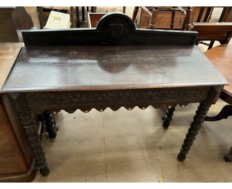 A 19th century oak side table with a shaped back above a rectangular top and carved frieze on bobbin turned legs and feet