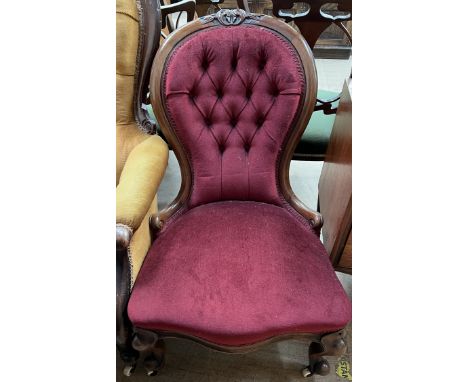 A Victorian mahogany framed nursing chair with a button back upholstered spoon back, with a pad seat on cabriole legs and cas