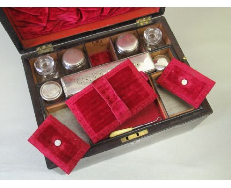 VICTORIAN ROSEWOOD TRAVELLING TOILET SET, THE HINGED TOP WITH MOTHER-OF-PEARL CARTOUCHE ENCLOSING A PARTLY FITTED RED VELVET 